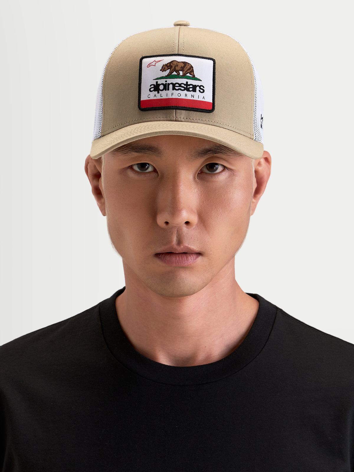 Alpinestars Cali 2.0 Gorra, gorra de estilo trucker sportswear, caqui y blanca, con visera curva y parche delantero de oso de California, vista frontal en modelo