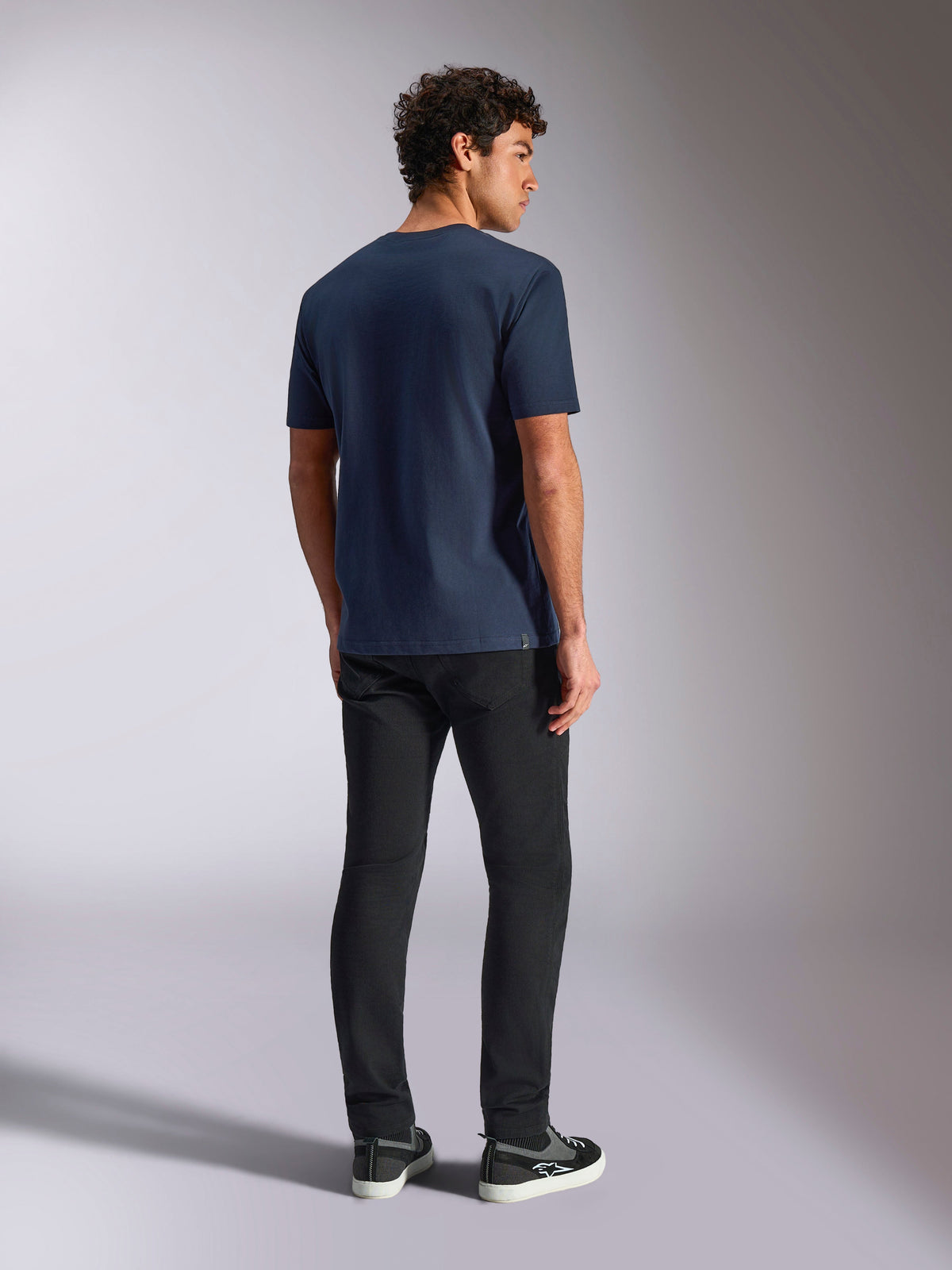 Alpinestars MX Helmet CSF Tee, camiseta de manga corta, azul marino, vista posterior en modelo, ropa deportiva casual inspirada en el motociclismo, combinada con pantalones negros y zapatillas