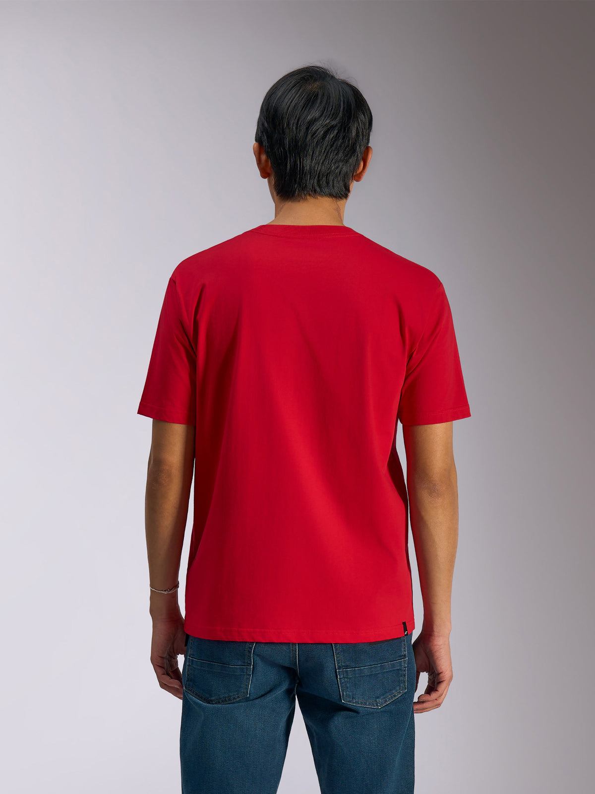 Alpinestars Ageless Shadow CSF Tee, vista trasera, camiseta de manga corta, roja, estilo casual de automovilismo, combinada con vaqueros azules