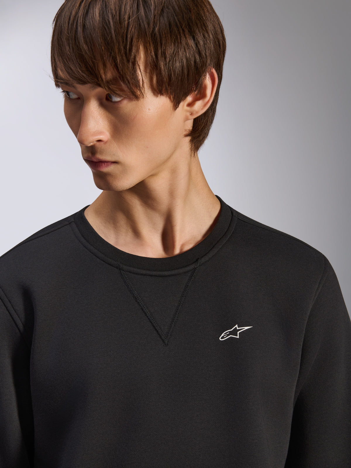 Sudadera Alpinestars Positive Crew, sudadera negra de cuello redondo con detalle de costura en V en el cuello, pequeño logotipo blanco de Alpinestars en el pecho izquierdo, moda urbana casual inspirada en el motociclismo