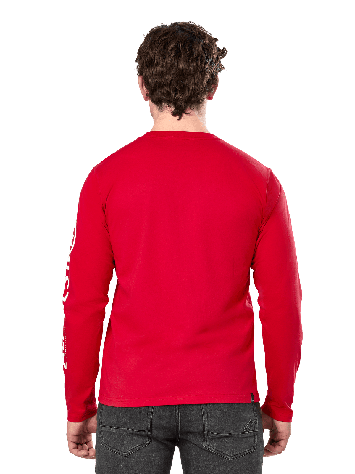 Vista trasera de un hombre con la camiseta de manga larga Alpinestars Committed CSF en color rojo, combinada con vaqueros gris oscuro, con el logotipo de Alpinestars visible en blanco en la manga y un diseño minimalista en la espalda.