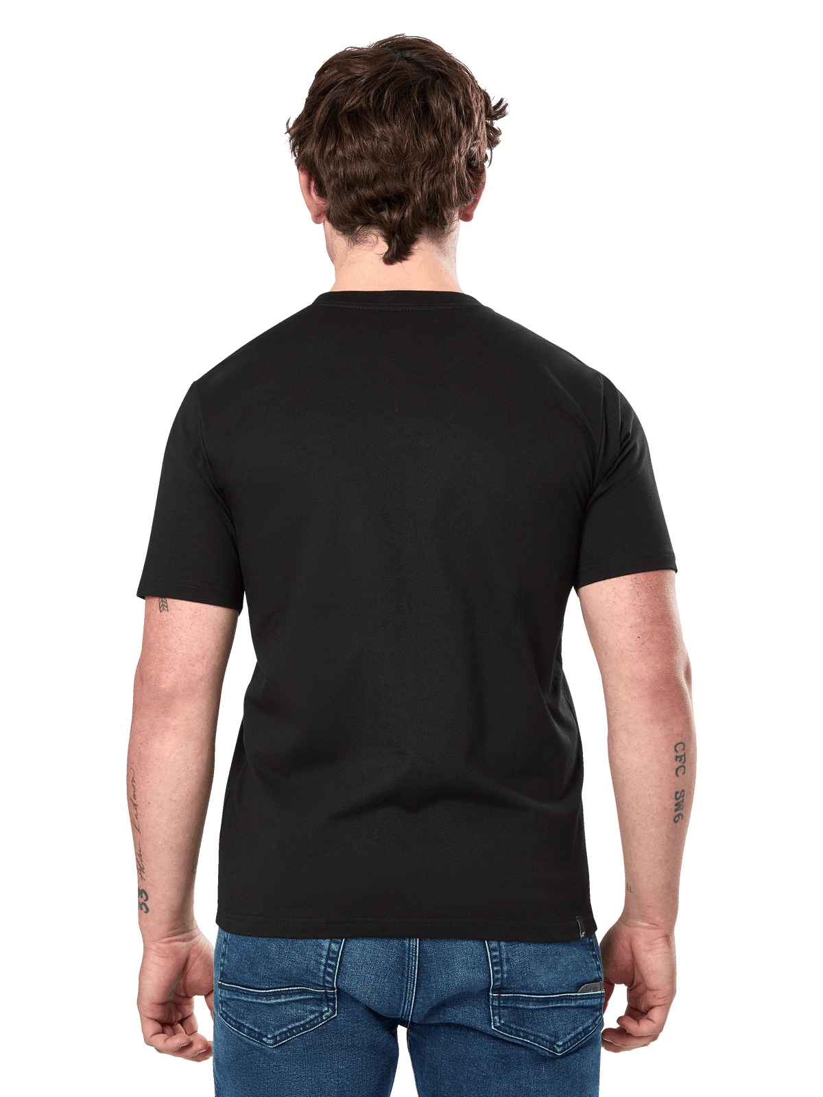 Alpinestars Dot Carbon CSF Tee, camiseta de manga corta, negra, vista trasera en modelo que muestra la espalda lisa y un ajuste casual, combinada con vaqueros azules, ropa urbana inspirada en el automovilismo