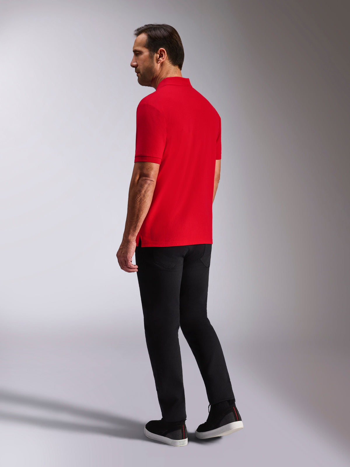 Alpinestars Polo Clásico Endeavor, polo de piqué de manga corta, rojo, vista posterior y lateral, con cuello y puños acanalados, combinado con pantalones y zapatos negros, ropa urbana casual de inspiración motorsport