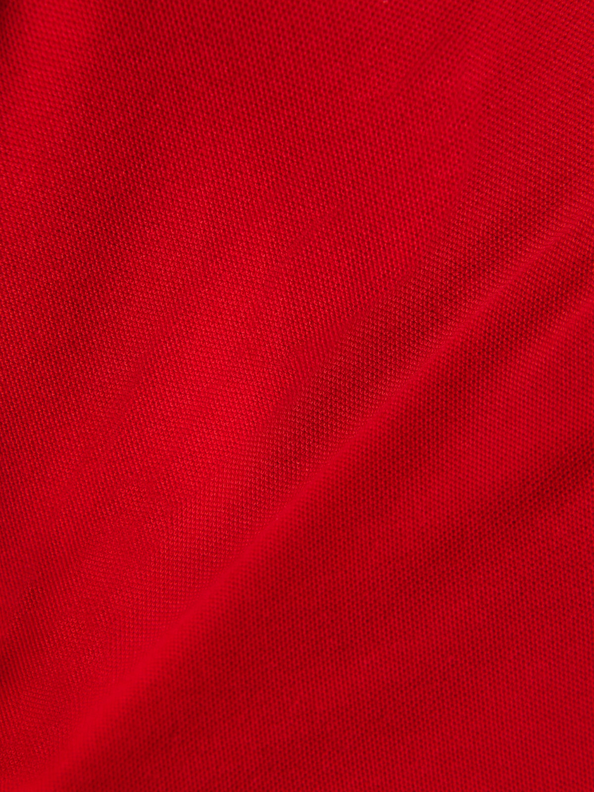 Alpinestars Endeavor Classic Polo, primer plano del tejido de piqué rojo, material de punto texturizado, mezcla de algodón y poliéster, ropa deportiva casual de motorsport