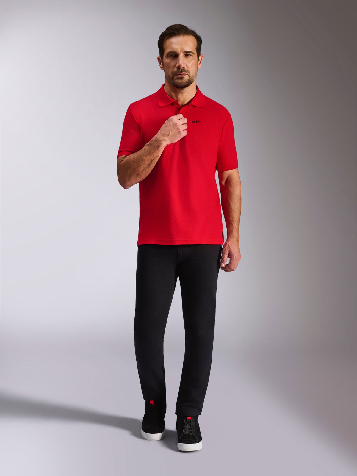Alpinestars Endeavor Classic Polo, polo de piqué rojo, de manga corta con logo Astars negro, cuello y puños de las mangas acanalados, combinado con pantalones negros y zapatillas, estilo casual inspirado en el automovilismo