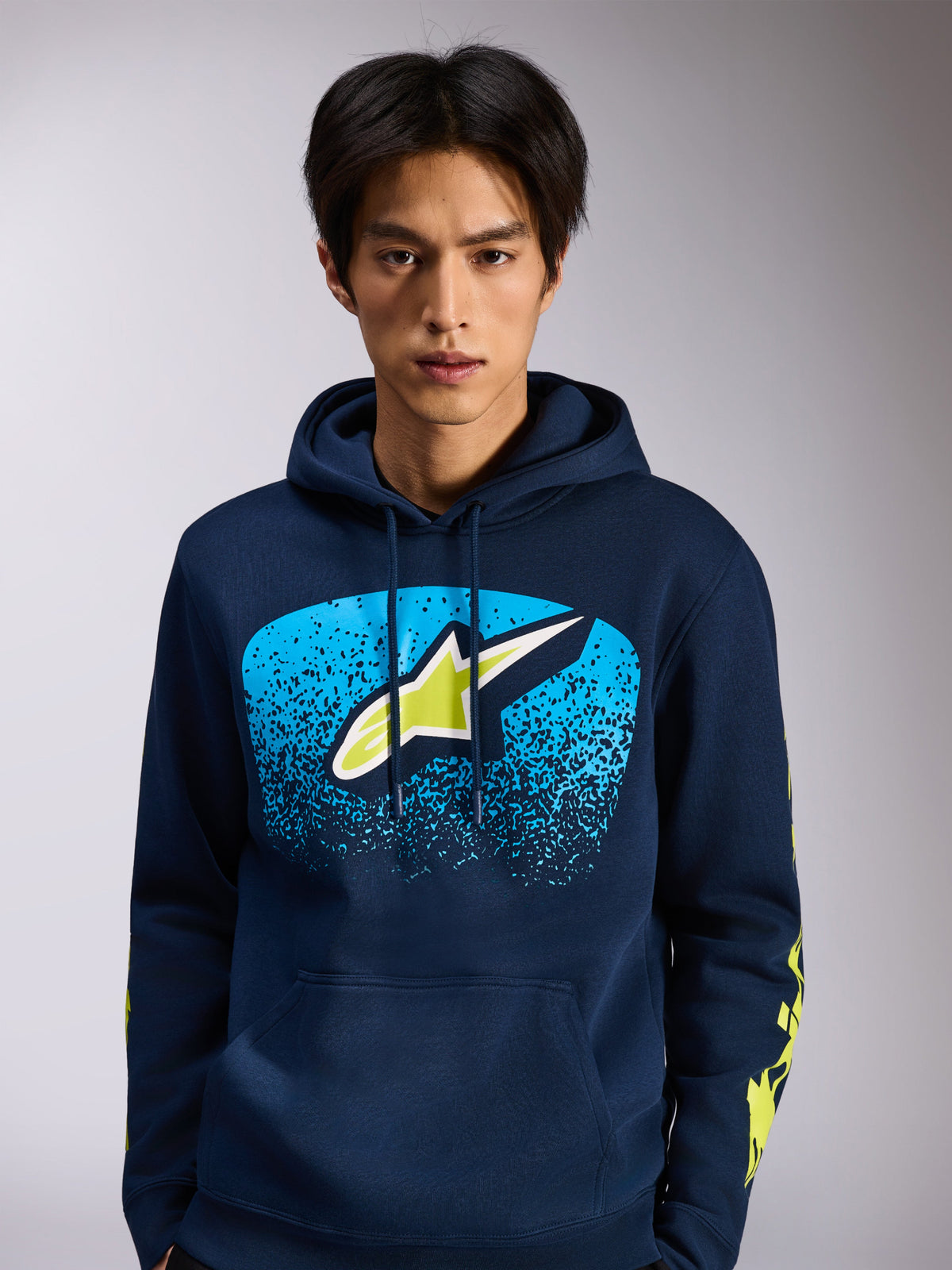 Alpinestars Obsessed Hoodie, sudadera de forro polar azul marino, logotipo frontal de Astars con degradado azul MX y detalles en verde lima, logotipos amarillos en las mangas, ropa urbana casual inspirada en el automovilismo