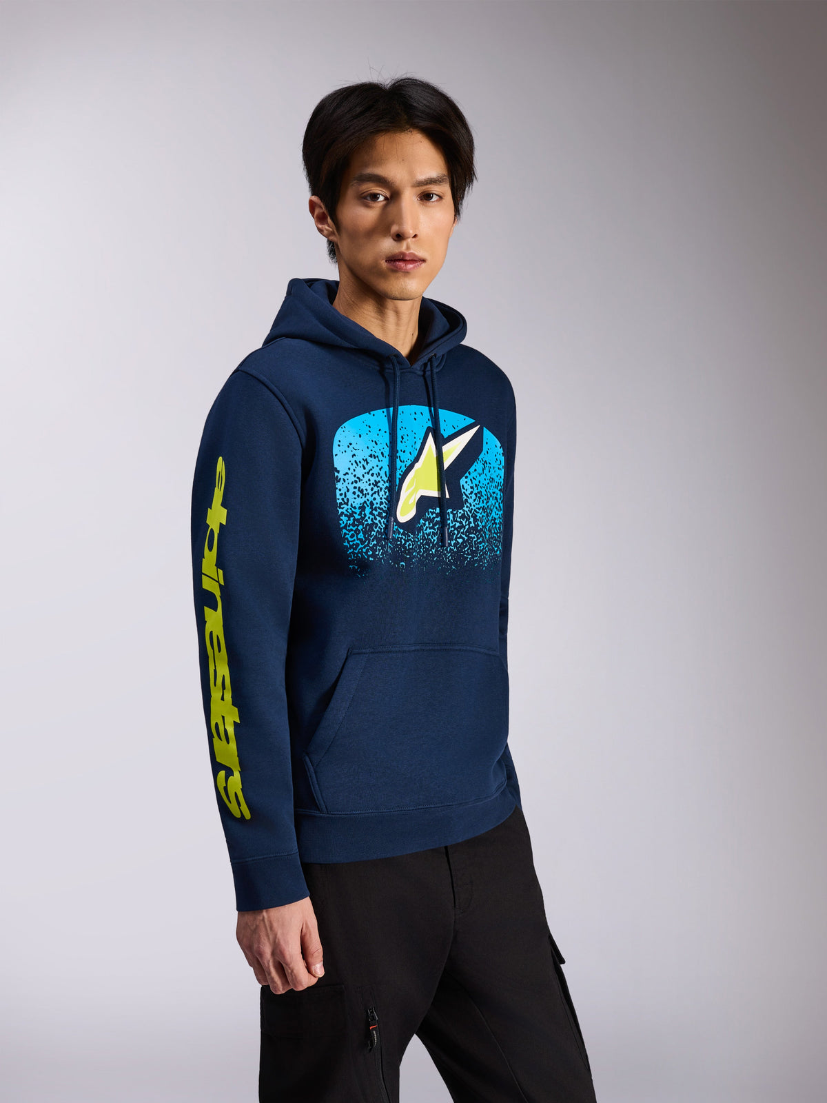 Alpinestars Obsessed Hoodie, azul marino, sudadera con capucha de forro polar, logo frontal de Astars con degradado MX azul claro y marca denominativa amarilla en la manga, capucha con cordón, estilo casual motorsport streetwear