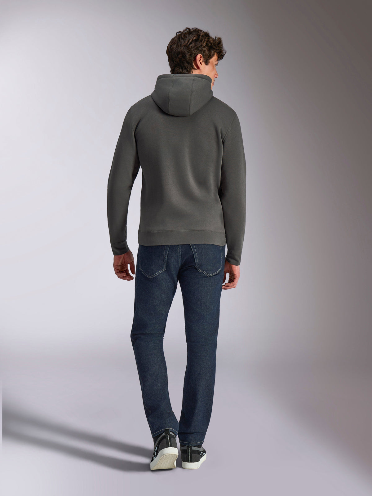 Alpinestars Ellipsoid Hoodie, sudadera con capucha gris gunmetal, vista trasera, lucida por un modelo con vaqueros oscuros y zapatillas negras, ropa urbana casual inspirada en el automovilismo