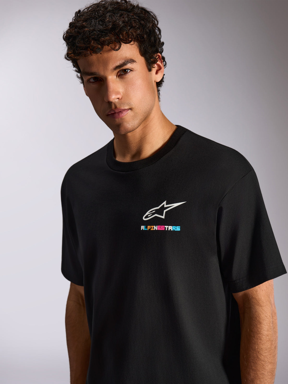 Alpinestars Wild Oversized CSF Tee, camiseta negra de manga corta para hombre con el logotipo blanco de Astars y marca multicolor vibrante en el pecho, estilo streetwear casual de motorsport