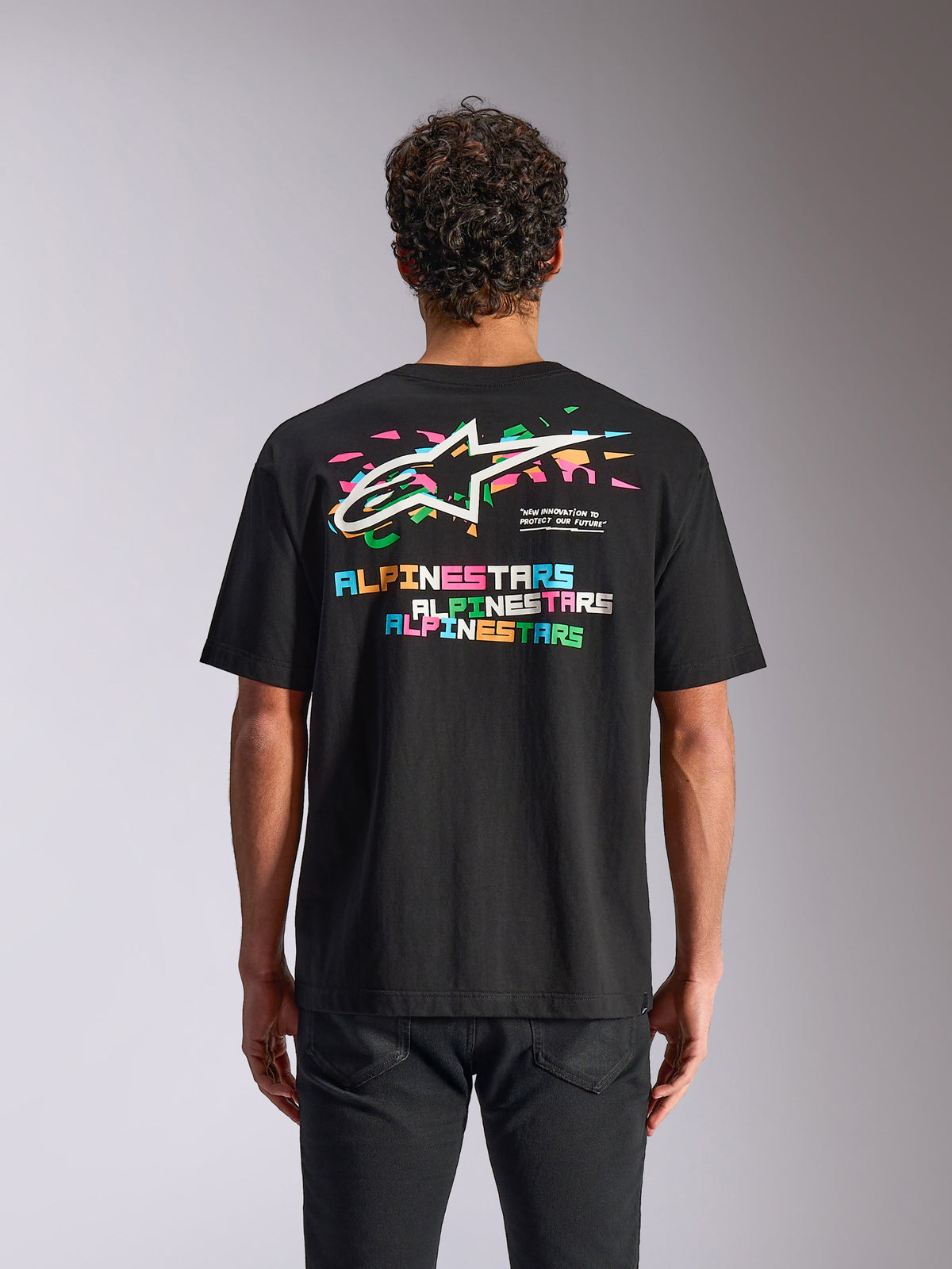 Alpinestars Wild Oversized CSF Tee, camiseta de manga corta, negra, vista posterior que muestra el vibrante logo de Astars multicolor y elementos gráficos, streetwear casual de motorsport