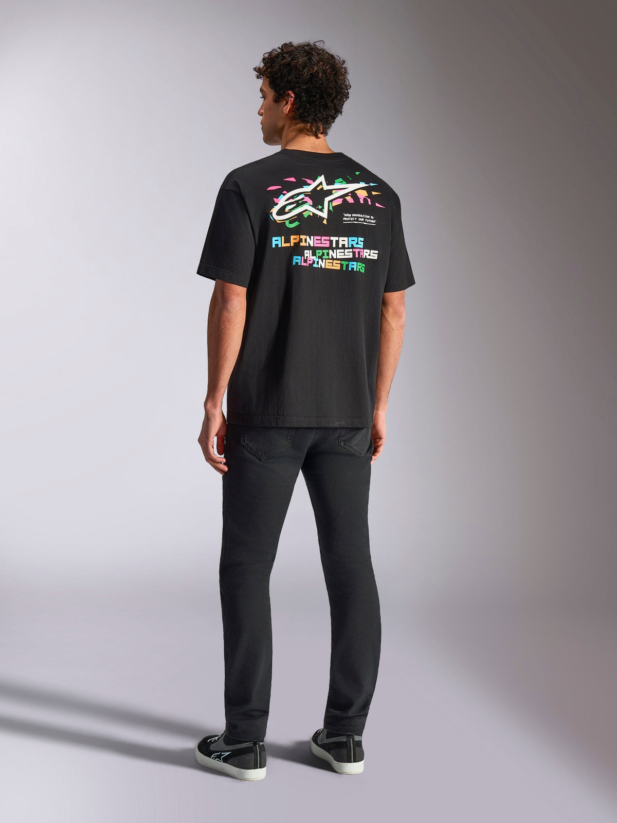 Camiseta Alpinestars Wild Oversized CSF, camiseta de manga corta en negro, con un gran gráfico multicolor en la espalda con el logo Astars y letras de colores, ajuste de gran tamaño, combinada con pantalones negros de corte ajustado para un look streetwear casual