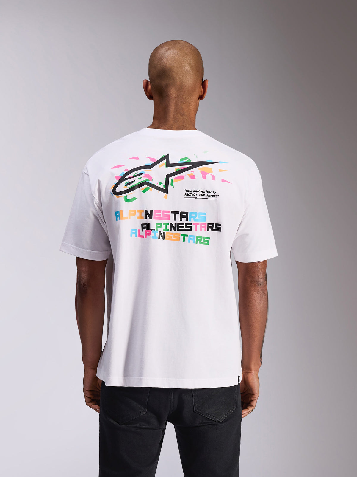 Camiseta Alpinestars Wild Oversized CSF, camiseta de manga corta, blanca, vista posterior con logotipos Astars vibrantes multicolor y estampados de texto, corte extragrande, ropa urbana casual de estilo motorsport