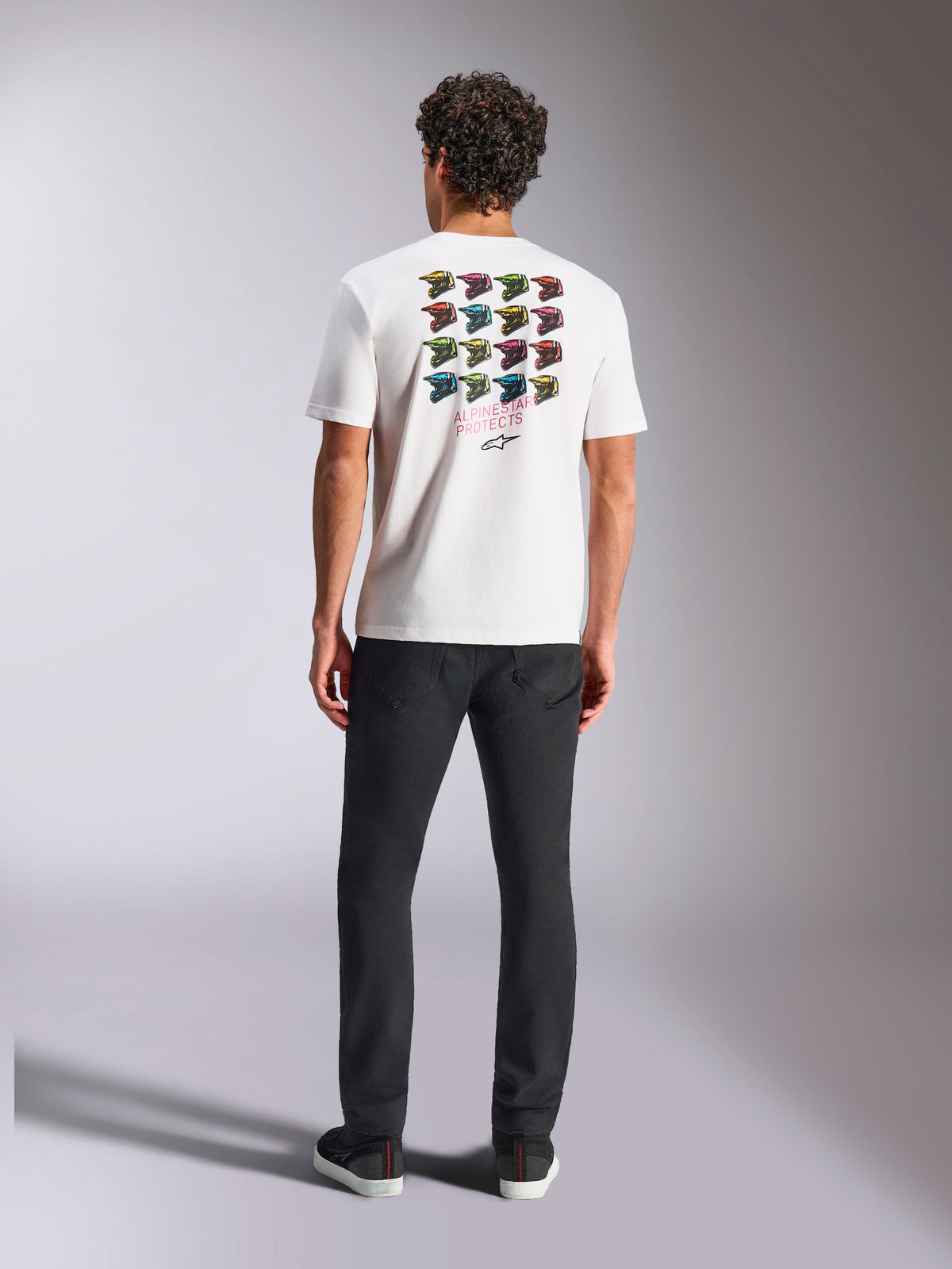 Camiseta Alpinestars Pop Helmet CSF, camiseta de manga corta, blanca, con un gráfico de cuadrícula de cascos M10 de colores en la parte posterior y el texto Alpinestars Protects, estilo casual streetwear de automovilismo