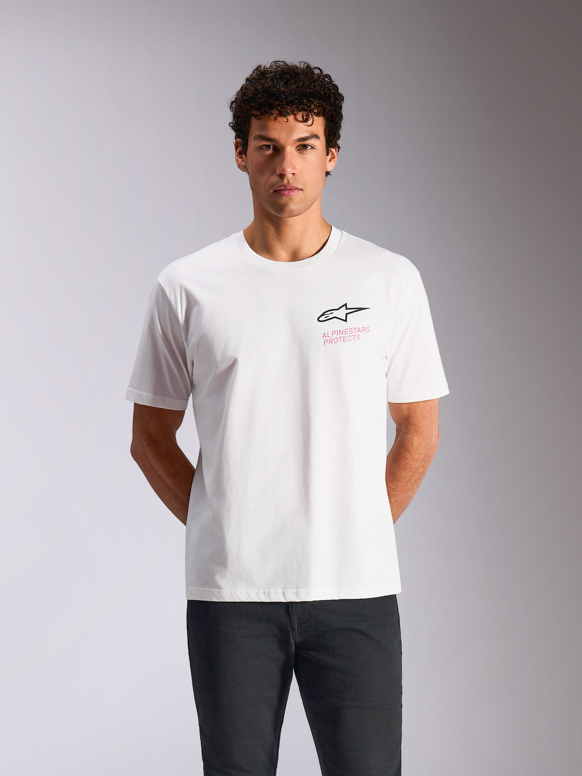 Alpinestars Pop Helmet CSF Tee, camiseta de manga corta, blanca, logo Astars negro con texto Alpinestars Protects en rosa, ropa urbana casual de inspiración motorsport