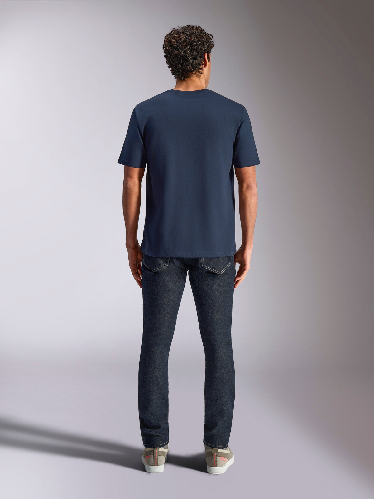 Alpinestars Trifecta CSF Tee, camiseta de manga corta, azul marino, vista trasera en modelo, combinada con vaqueros oscuros y zapatillas casuales, estilo streetwear casual de motorsport