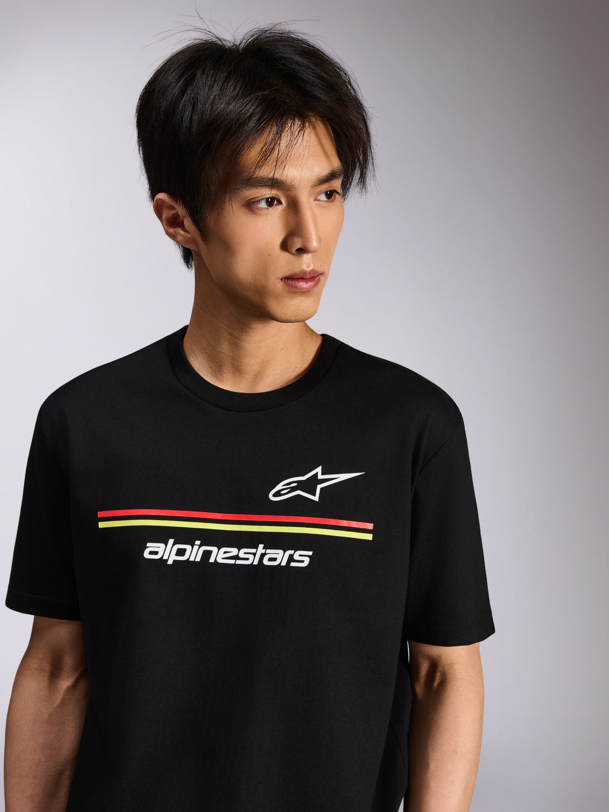 Alpinestars Lanes CSF Tee, Short Sleeve T-Shirt, Black, featuring white Astars and Alpinestars logos with red and yellow stripes, Casual Motorsport Streetwear worn by a model