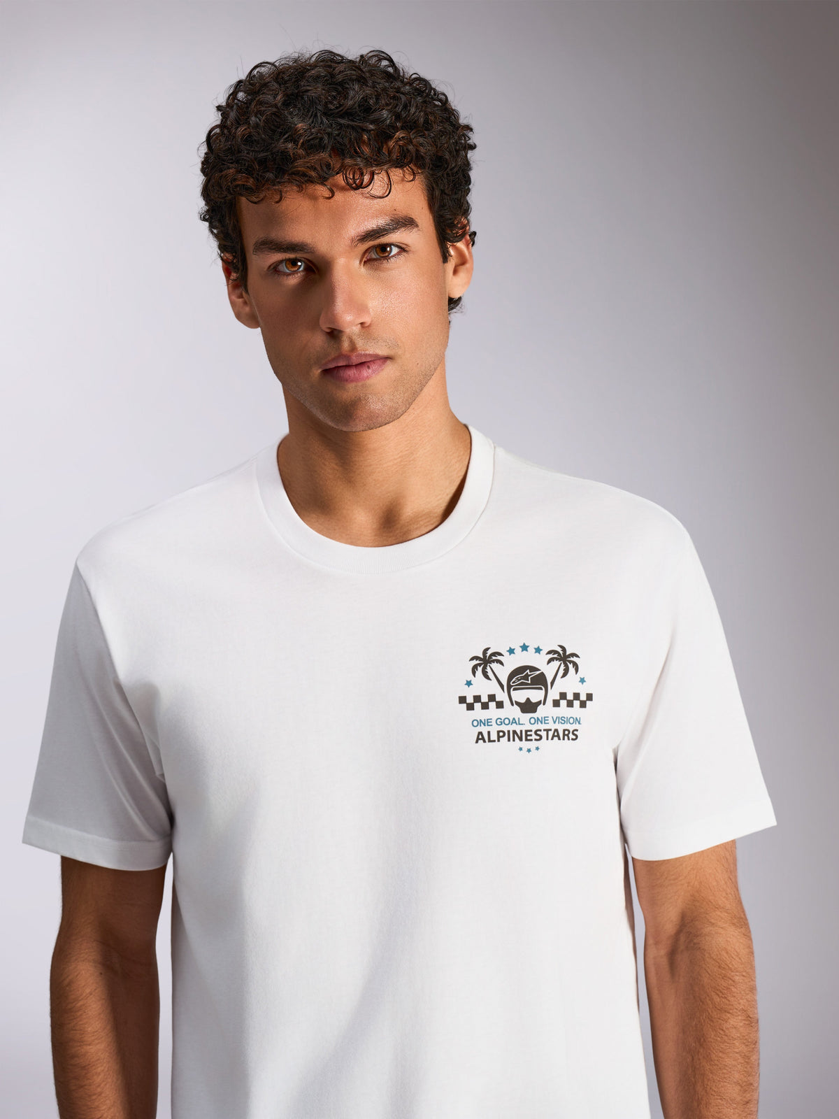 Camiseta Alpinestars Order CSF, camiseta de manga corta blanca, estampado gráfico con casco y palmeras, texto "One Goal. One Vision.", ropa deportiva casual de motor