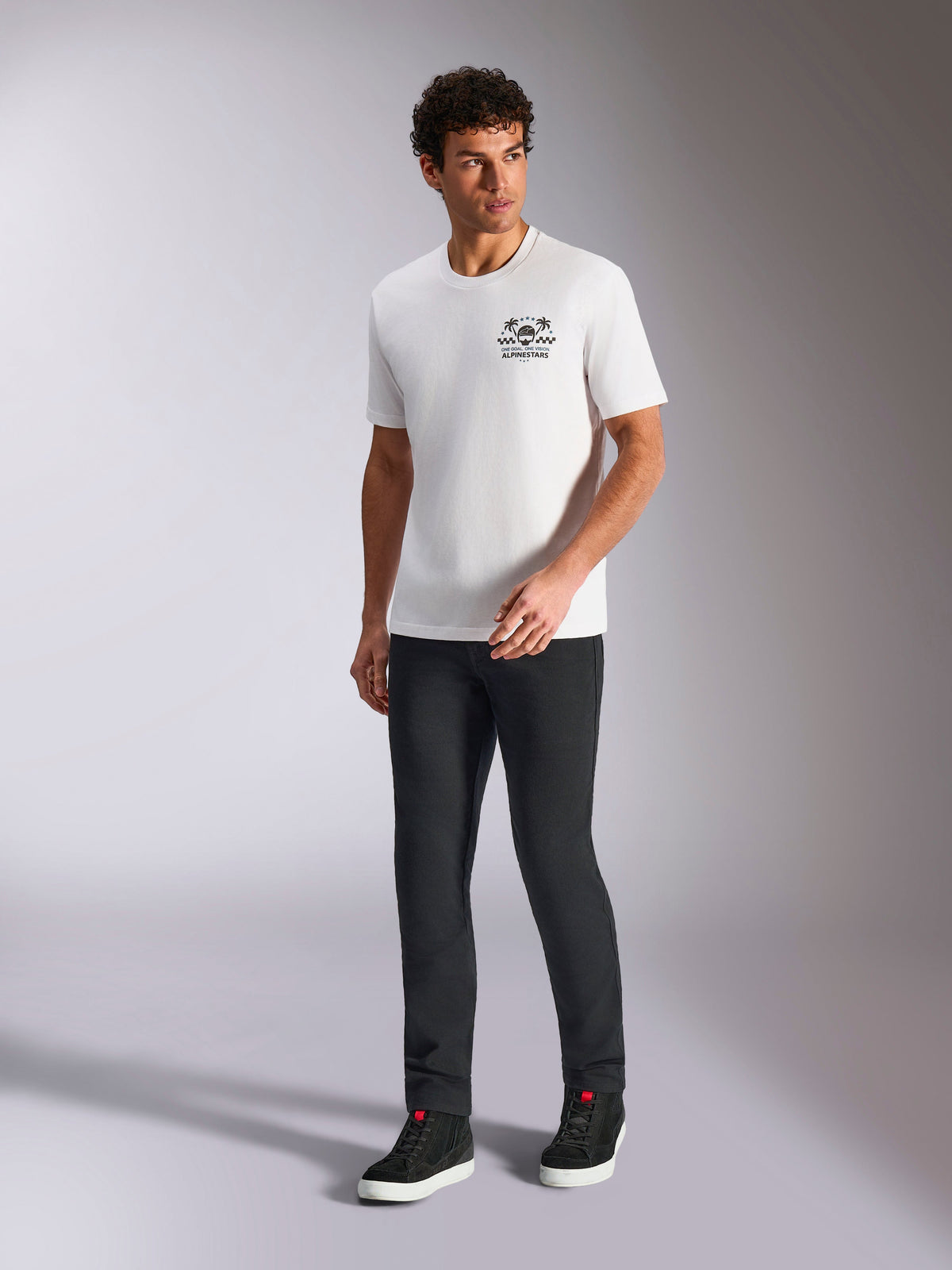 Alpinestars Order CSF Tee, camiseta de manga corta, blanca, logotipo de casco y palmeras, combinada con pantalones negros y zapatillas de caña alta, estilo streetwear casual de automovilismo