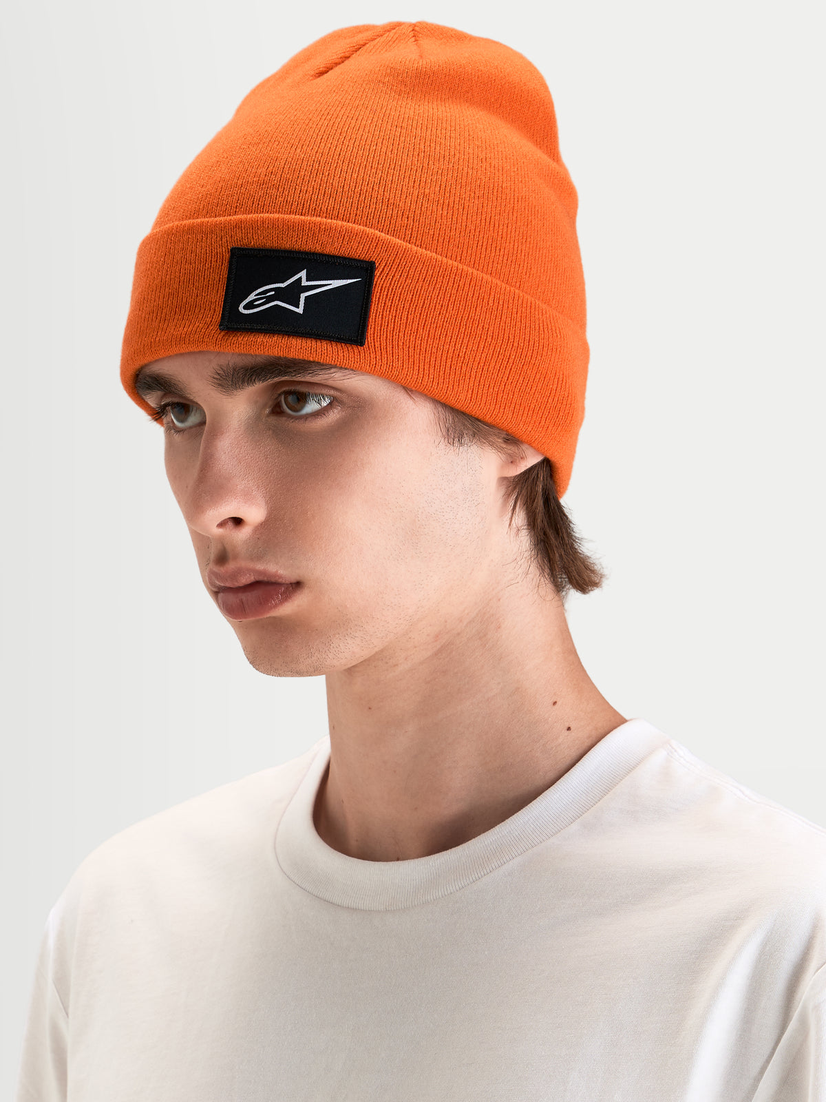 Gorro Augment Cuff Alpinestars, gorro de punto naranja con parche tejido del logo Astars en negro y blanco, vista en modelo con sportswear casual