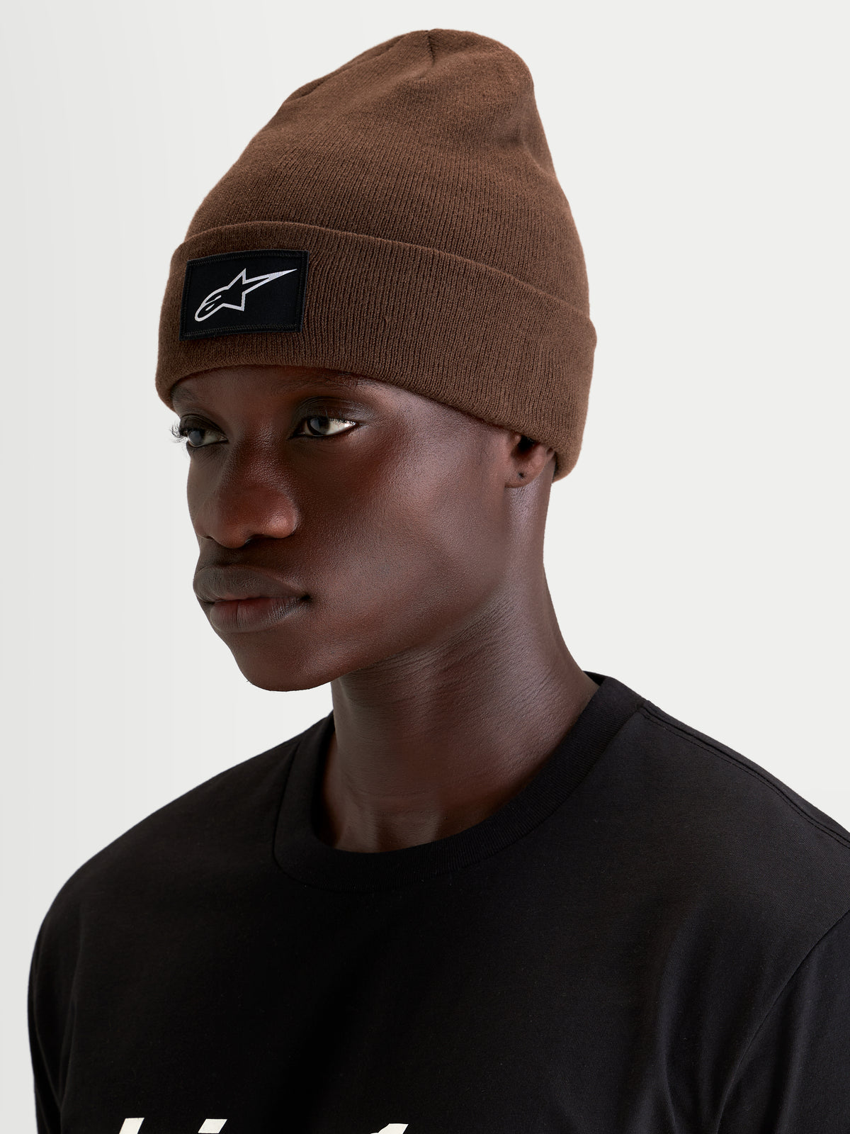 Alpinestars Gorro Augment Cuff, gorro de punto sportswear, marrón, con parche tejido con el logo en blanco y negro en el dobladillo, puesto en modelo