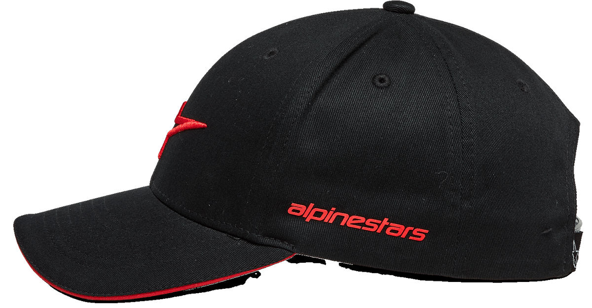 Gorra Alpinestars Rostrum, gorra de béisbol negra y roja, vista de perfil lateral, visera curvada con borde tipo sándwich rojo, logotipo bordado en 3D en la parte frontal, nombre Alpinestars en rojo en el lateral, estilo casual motorsport streetwear