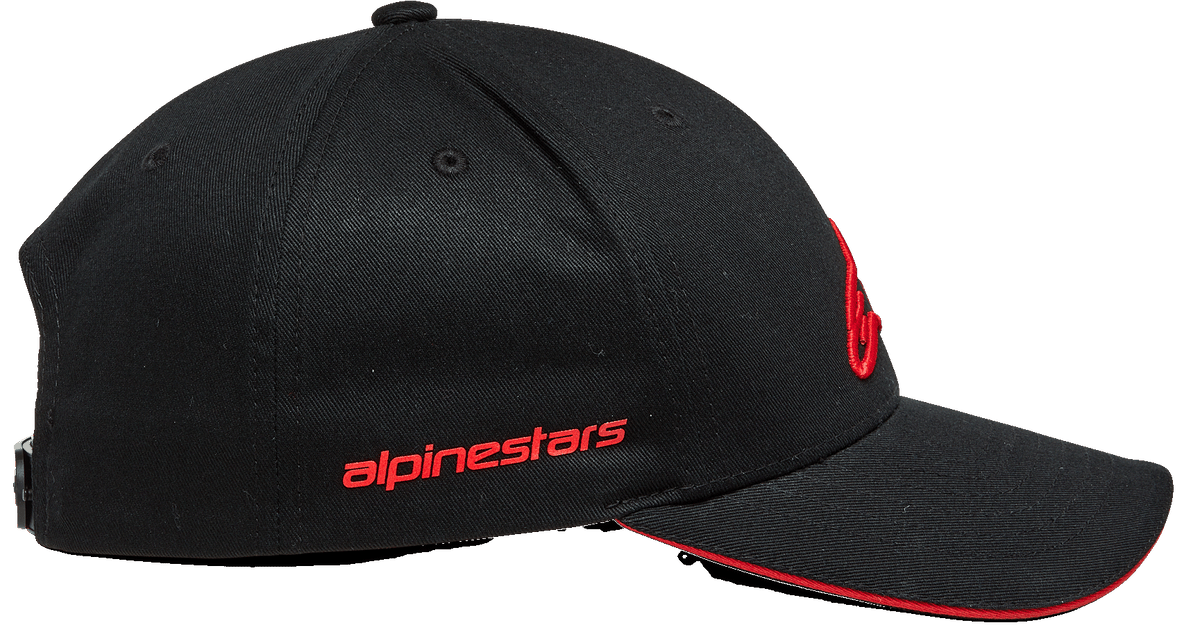 Gorra Alpinestars Rostrum, gorra snapback con visera curvada, color negro y rojo, vista de perfil lateral con logotipo Alpinestars en rojo, copa estructurada y borde de la visera tipo sándwich en rojo, accesorio inspirado en el automovilismo