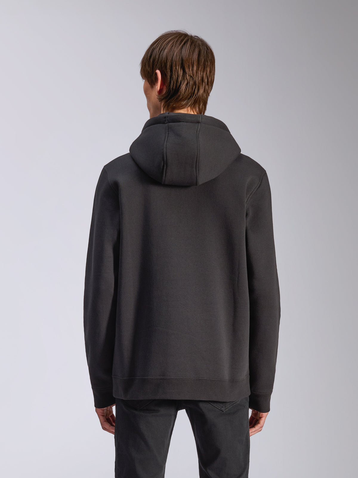 Sudadera con capucha Alpinestars Harken, negro, vista trasera de modelo masculino usando sudadera de forro polar casual, puños y dobladillo de canalé, estilo streetwear moderno inspirado en el automovilismo