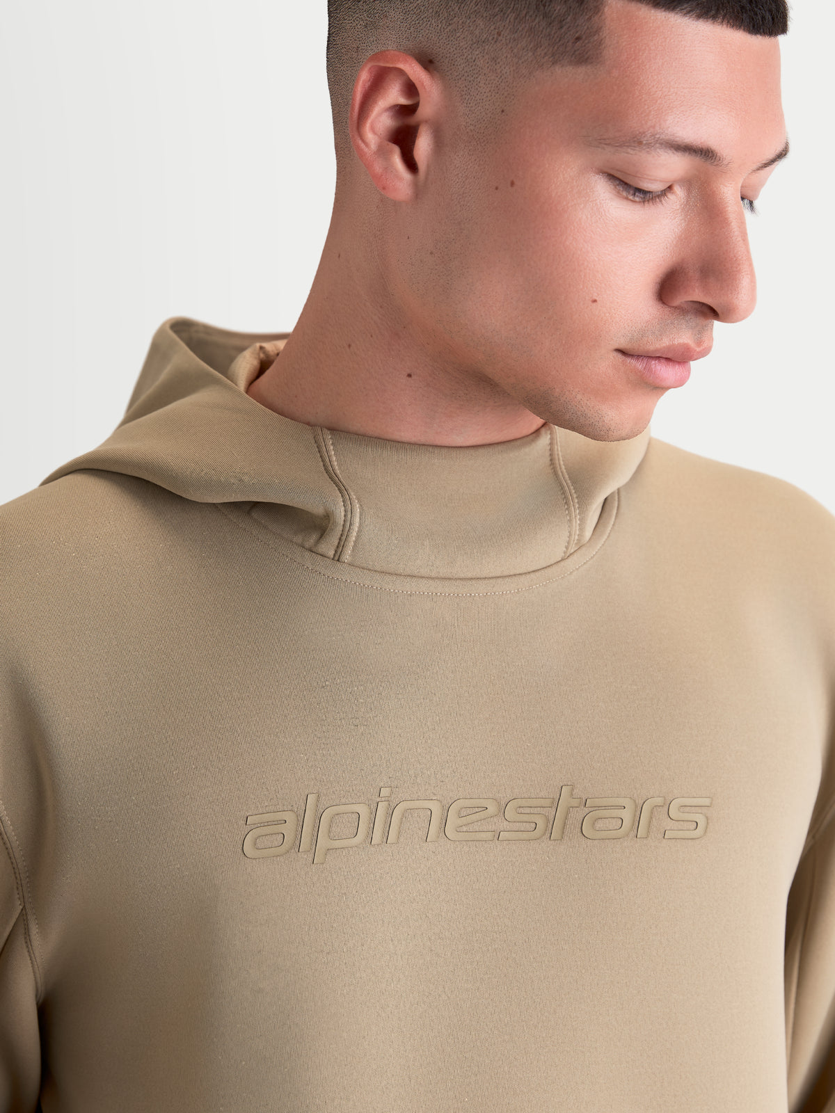 Alpinestars sudadera con capucha Datrix, pulóver de ropa deportiva para hombre y mujer, marrón, con logotipo Alpinestars tonal y capucha con forro de malla, primer plano en modelo que muestra la construcción de forro polar premium