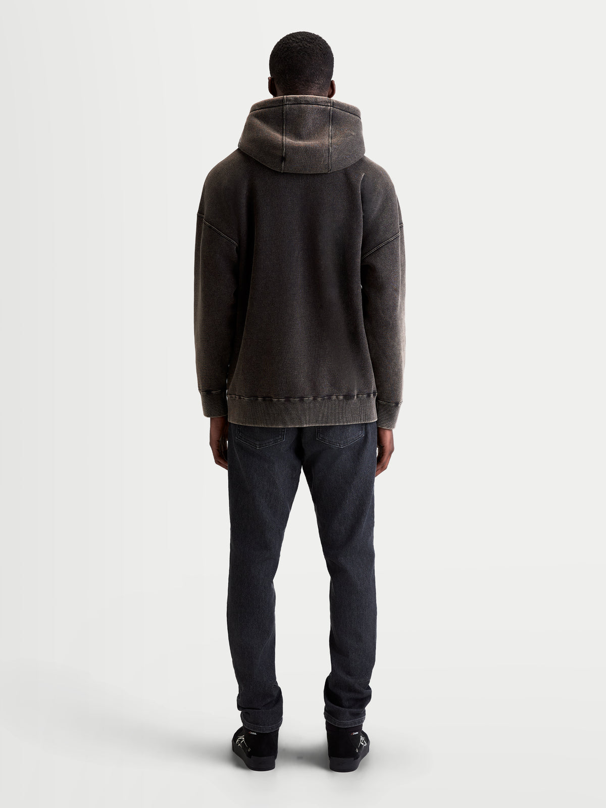 Alpinestars sudadera con capucha Infinite Washed Oversize, sudadera de forro polar para uso casual, unisex, color negro lavado con acabado efecto nieve, vista trasera que muestra el ajuste relajado, la capucha y el dobladillo de canalé.
