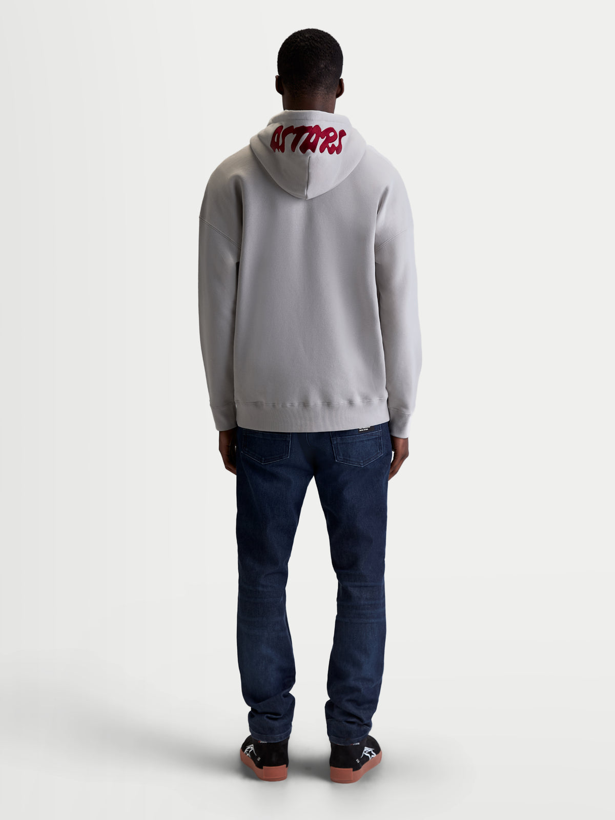 Alpinestars Sudadera con capucha Pioneer Oversized, sudadera deportiva de forro polar con cremallera, gris cemento y rojo, vista trasera en modelo con logotipo ASTARS bordado en la capucha y ajuste relajado oversized