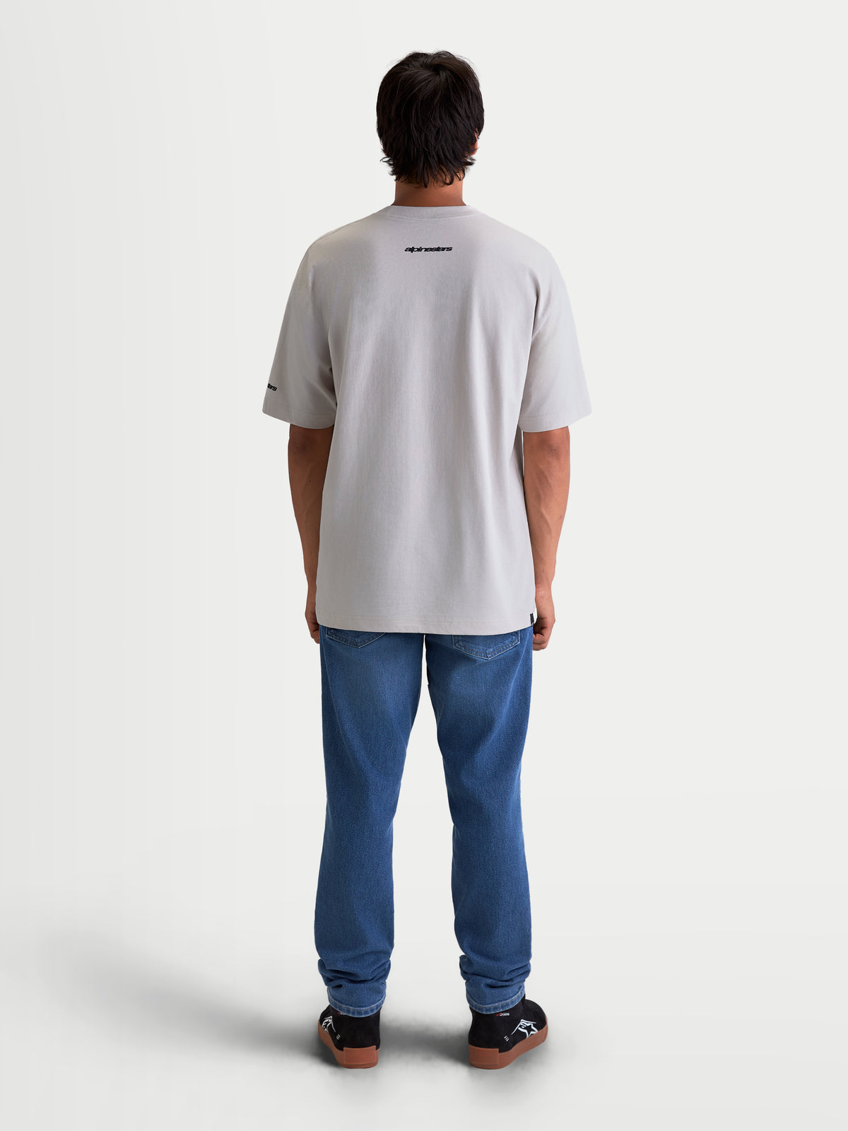 Alpinestars Mandate Oversized CSF Tee, Unisex Sportswear, Cement Gray, Back View on Model. Relaxed Oversized Fit Short Sleeve T-Shirt featuring a black Alpinestars wordmark graphic on the upper back, crafted from a soft cotton-poly blend for daily comfort.