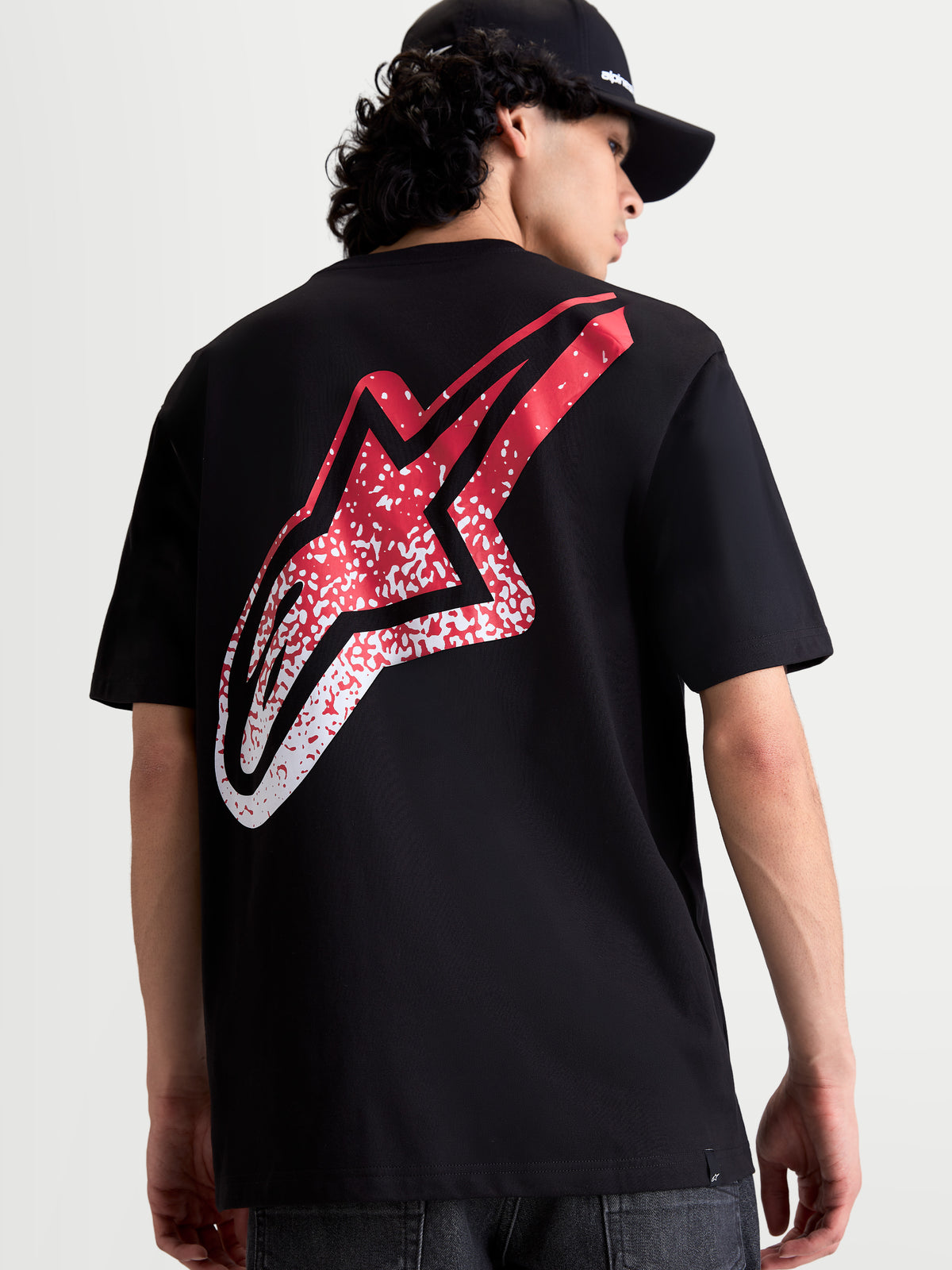 Alpinestars Meteor CSF, camiseta de mangas cortas para hombre, negra, vista trasera con gran logotipo Astars degradado en rojo y blanco inspirado en el MX, ropa casual de motorsport