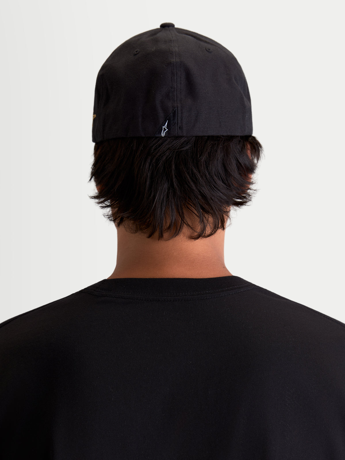 Alpinestars Gorra County Canvas, gorra sportswear negra, vista trasera sobre modelo, con ajuste flex-back y logotipo Astars bordado en la parte posterior, material de lona Oxford para uso casual