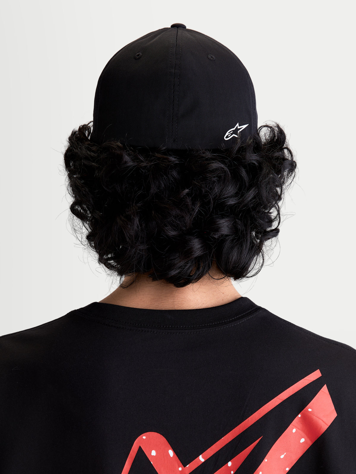 Alpinestars Gorra Points, gorra de estilo sportswear con ajuste flex-back, unisex, negra y blanca, confeccionada en nailon tactel ligero, vista trasera sobre modelo con logotipo Astars HD blanco.