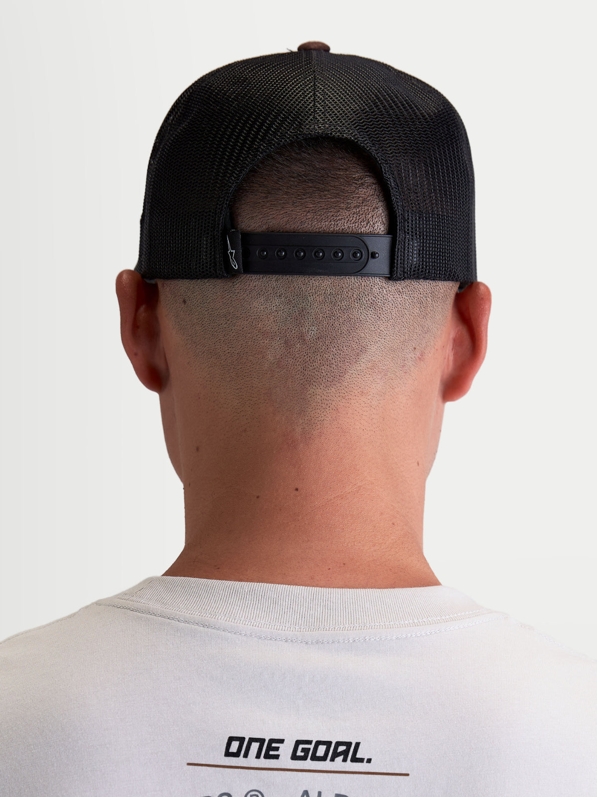 Alpinestars Gorra Hotlink, gorra de estilo casual de inspiración motorsport, unisex, marrón y negra, vista trasera en modelo con cierre snapback ajustable y paneles de malla transpirable.