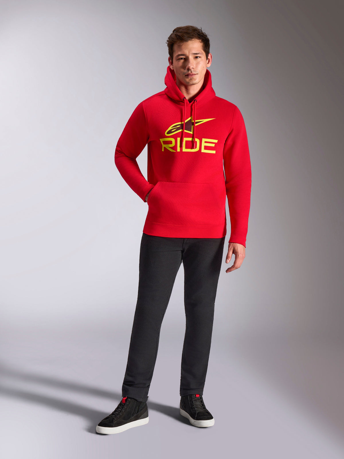 Alpinestars Ride V3 Hoodie, Red Pullover Fleece, Bright Yellow RIDE logo with Astars symbol on chest, worn with black pants and black high-top sneakers, casual motorsport-inspired streetwear