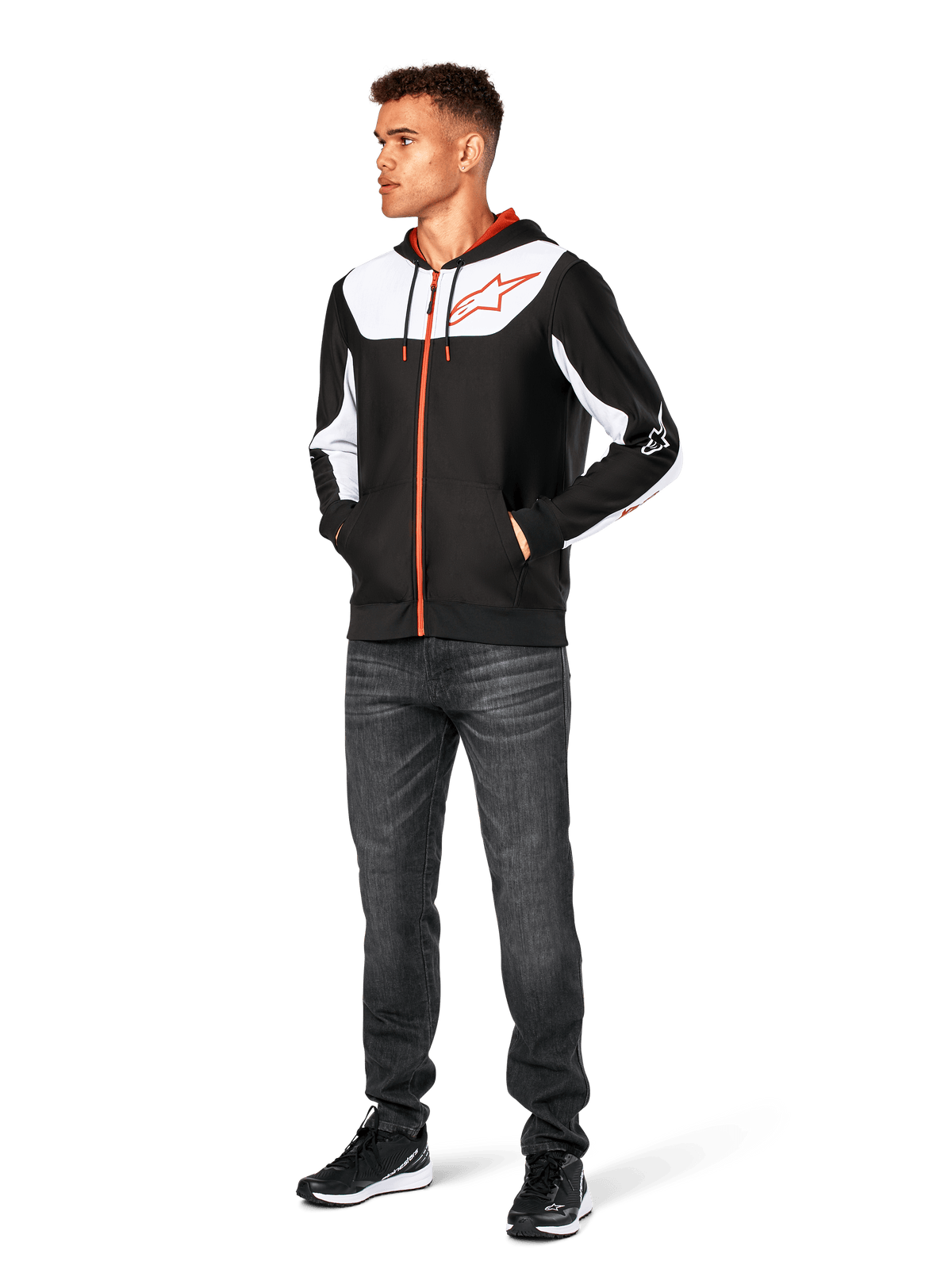 Sudadera Alpinestars Sessions V3, sudadera casual con cremallera frontal, negro, blanco y rojo, lucida por un modelo con vaqueros oscuros y zapatillas negras, con paneles de bloques de color blanco en el pecho y las mangas, detalles de cremallera y cordón en rojo, logotipo grande en el pecho, ropa urbana de forro polar inspirada en el automovilismo