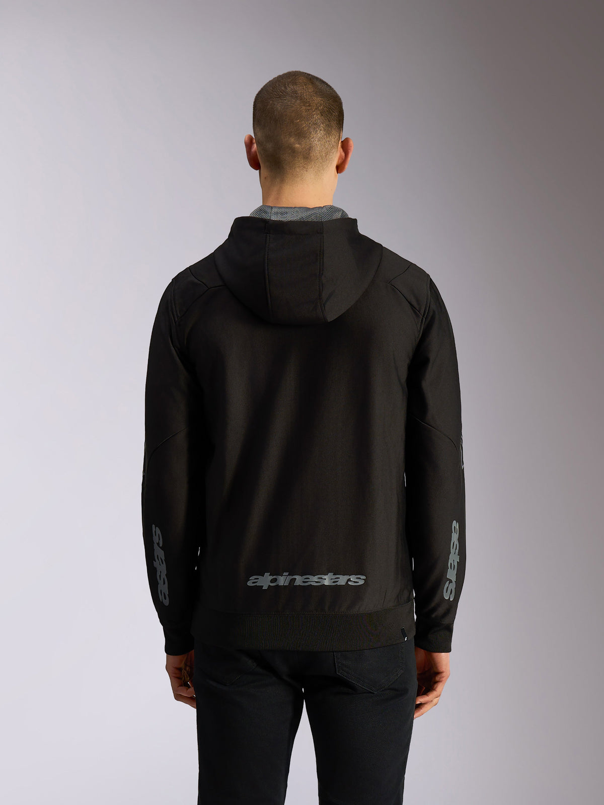 Alpinestars Sessions V3 Hoodie, vista trasera, sudadera negra con cremallera y logotipo gris de Alpinestars en la parte inferior de la espalda, marca Astars en las mangas, dobladillo y puños de canalé, estilo casual de automovilismo