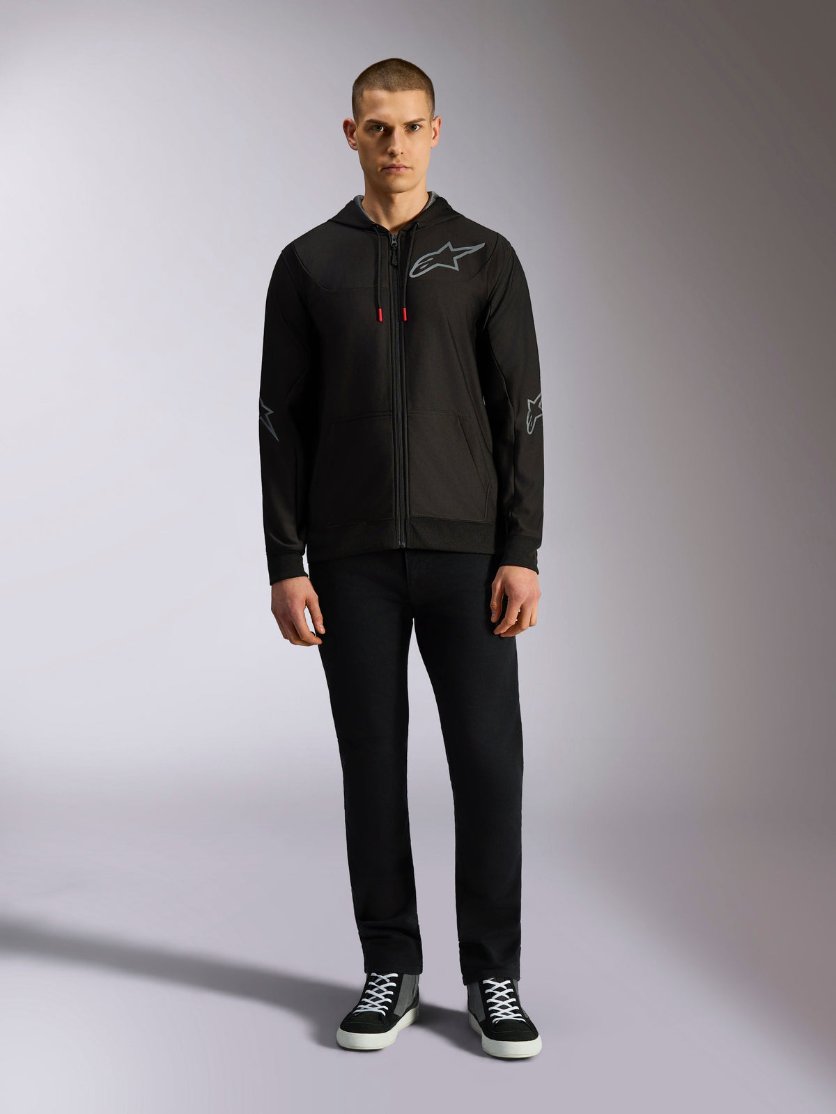 Alpinestars Sessions V3 Hoodie, sudadera con capucha de forro polar y cremallera frontal, negra con logotipo Astars gris en el pecho y las mangas, cordones con puntas rojas, ropa urbana casual inspirada en el automovilismo.
