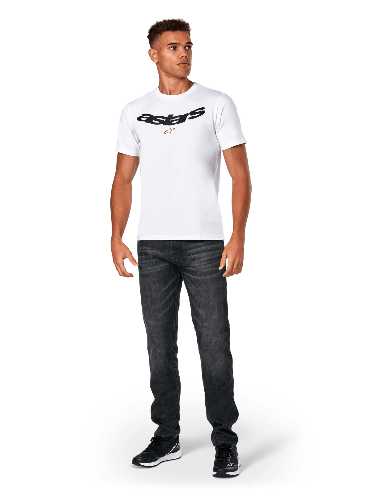 Alpinestars Elliptic CSF Tee, camiseta de manga corta, blanca, logo Astars arqueado en negro con símbolo de estrella naranja, usada por un modelo con vaqueros negros y zapatillas, ropa de calle casual de estilo motorsport