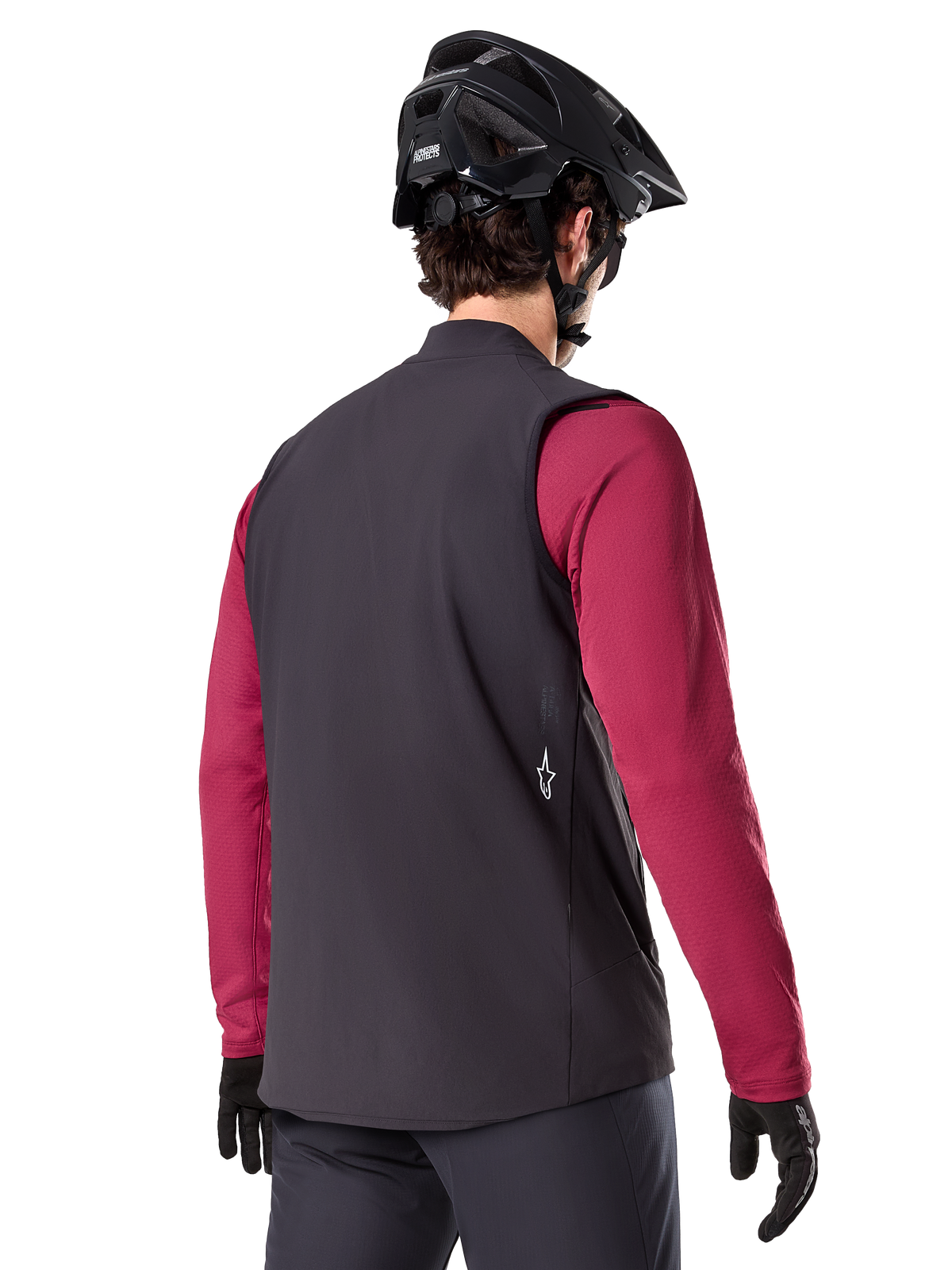 Chaleco térmico Alpinestars A-Dura, negro, vista trasera, puesto sobre un jersey granate de manga larga con casco y guantes negros de MTB, equipamiento de ciclismo ligero y aislado para rutas todoterreno