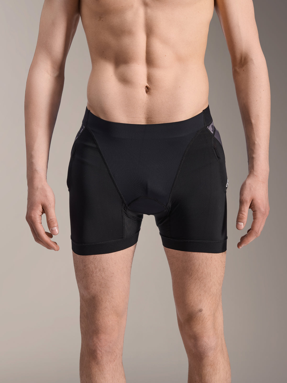 Alpinestars Boxers de Protección A-Motion Plasma, pantalones cortos de protección para MTB, negros con detalles de camuflaje negro, vista frontal en modelo masculino, con malla elástica transpirable y protección de cadera integrada para el rendimiento en ciclismo.
