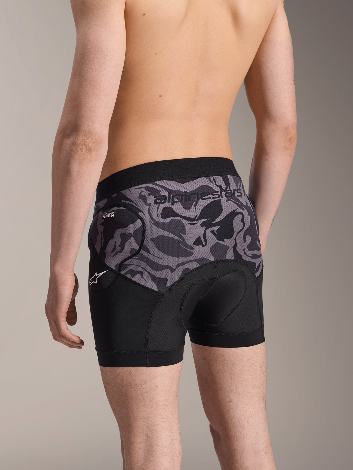 Alpinestars A-Motion Plasma Protection Boxers, pantalones cortos de protección para ciclismo en Black Camo, vista trasera que muestra el diseño ergonómico con protección de cadera Nucleon Plasma y almohadilla de gamuza, material de malla transpirable con logo de Alpinestars en la cintura