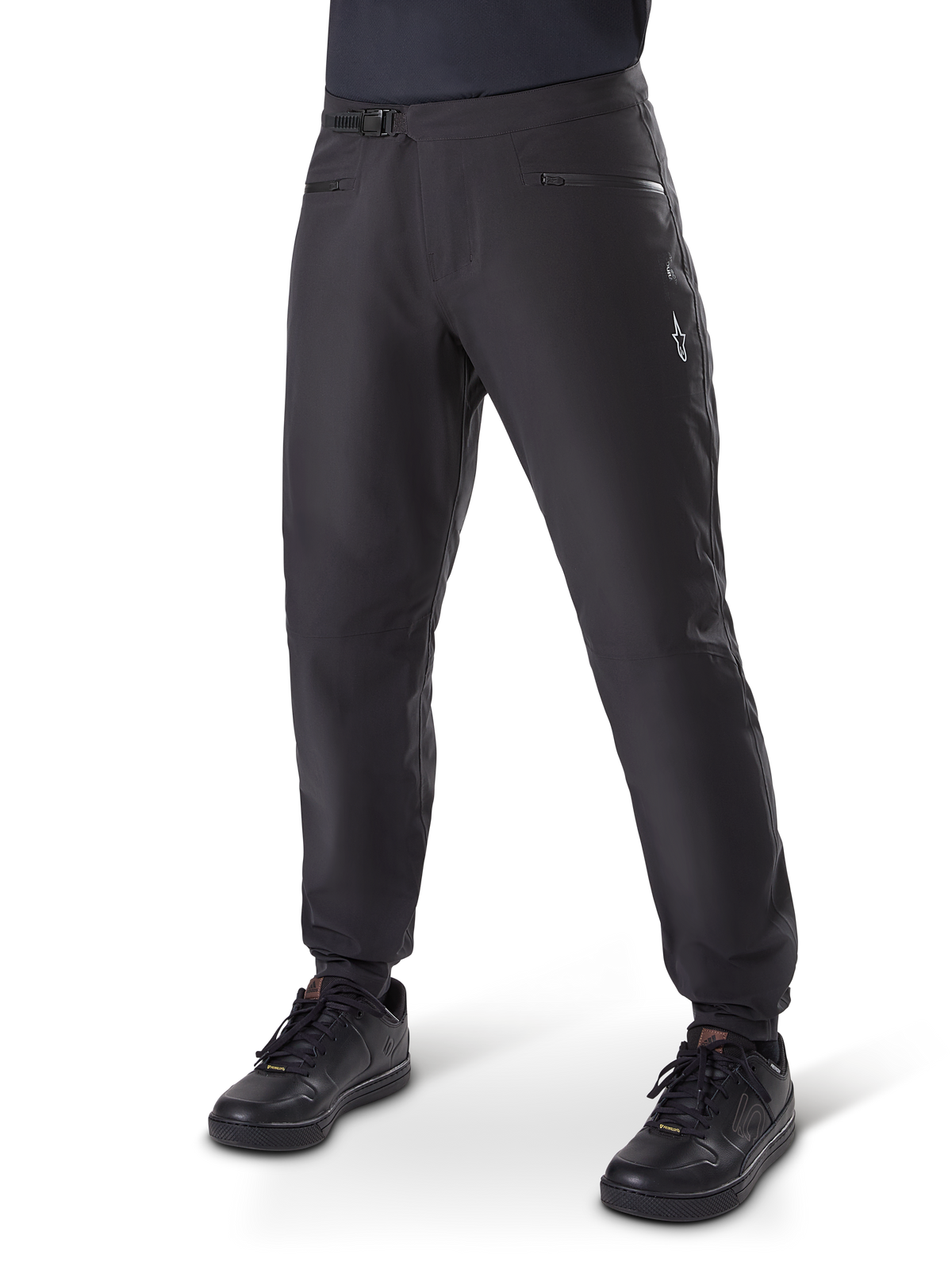 Alpinestars A-Dura Waterproof Pants, MTB Cycling Pants, Black, featuring a ratchet waist closure, zippered pockets, and a white Astars logo on the thigh, shown worn with black cycling shoes for all-weather trail riding