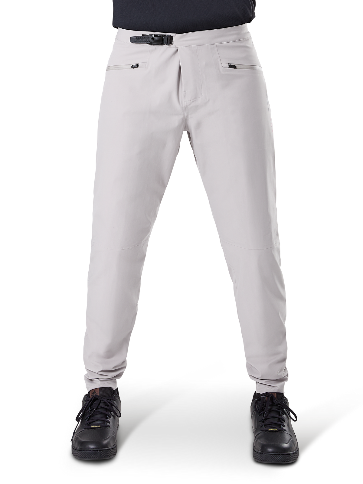 Pantalones impermeables Alpinestars A-Dura, pantalones de ciclismo MTB, gris titanio, vista frontal, con cierre de trinquete negro en la cintura y dos bolsillos con cremallera, puños elásticos, usados con zapatillas negras, equipo técnico impermeable para ciclismo de montaña