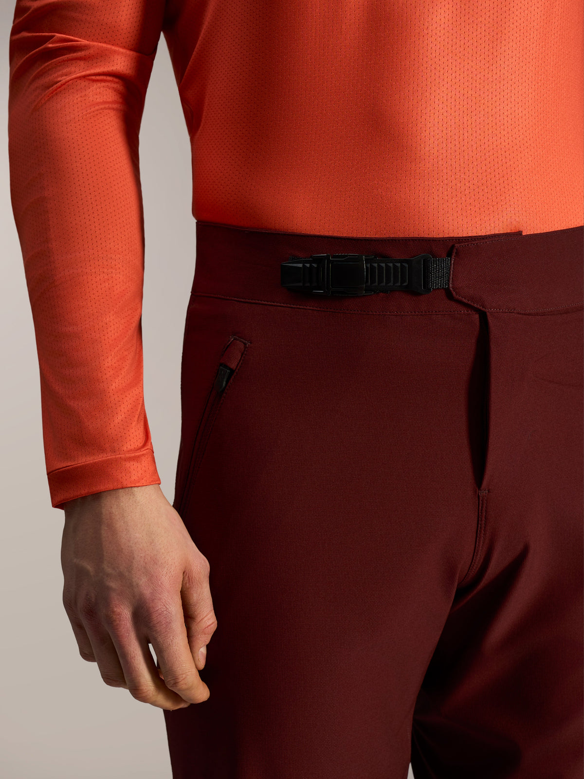 Pantalones cortos A-Dura Ride burdeos, detalle de cierre de trinquete frontal y bolsillo con cremallera para MTB.