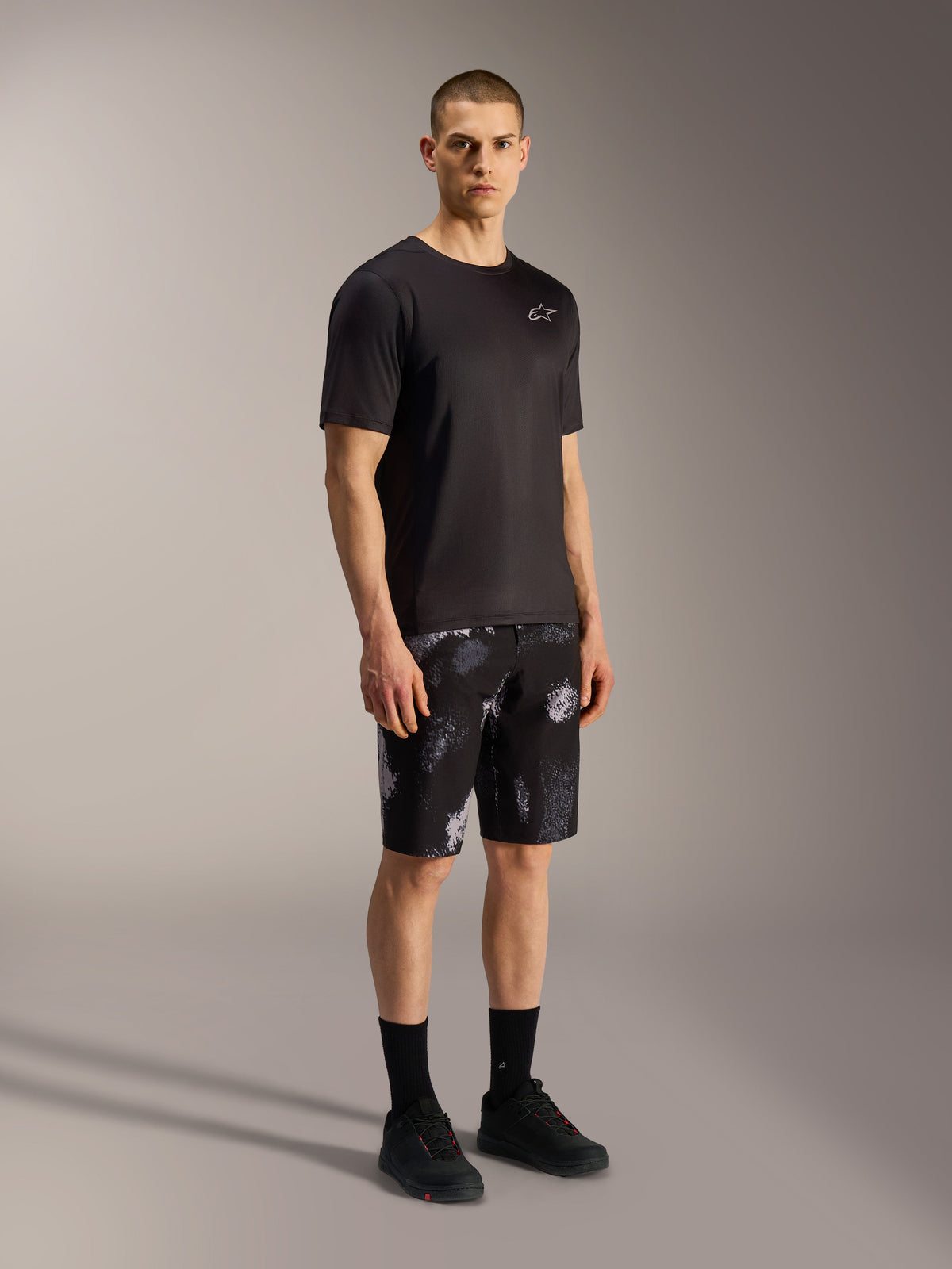 A-Dura Ride Pantalones cortos en Black Camo, shorts de MTB Alpinestars con camuflaje gris, jersey y calzado negro.
