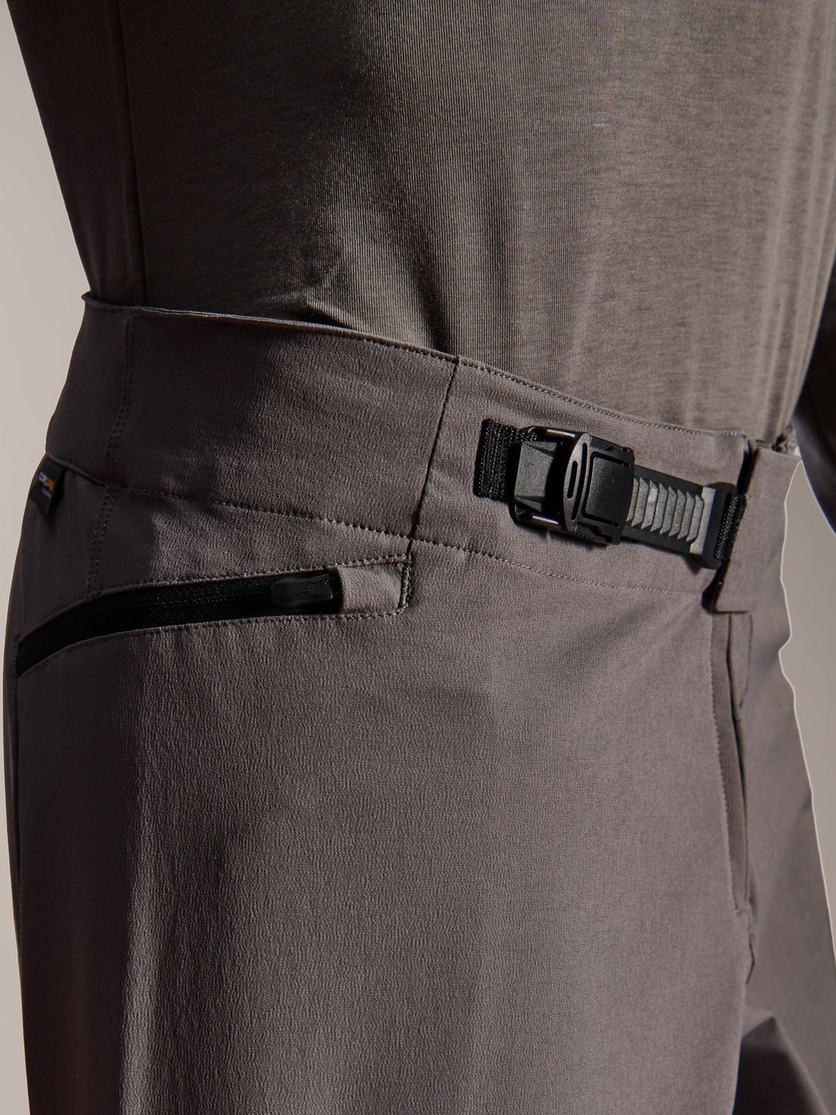 Alpinestars A-Dura Elite Pants, pantalones de MTB, gris oscuro, vista de primer plano que muestra el sistema de cierre frontal de trinquete y el bolsillo con cremallera, equipamiento técnico de ciclismo para bicicleta de montaña