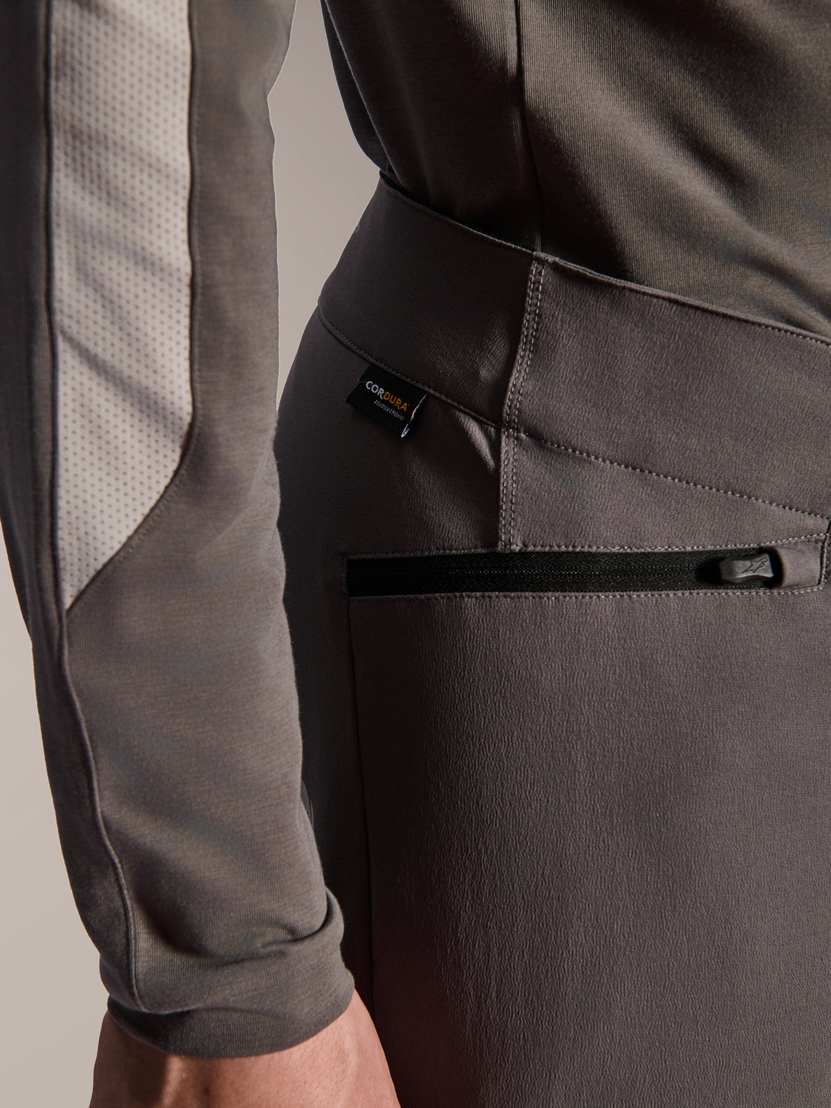 Alpinestars A-Dura Elite Pants, pantalones de mountain bike gris oscuro, detalle de primer plano del bolsillo lateral con cremallera y etiqueta de tejido Cordura, tejido elástico en 4 direcciones duradero para rendimiento off-road