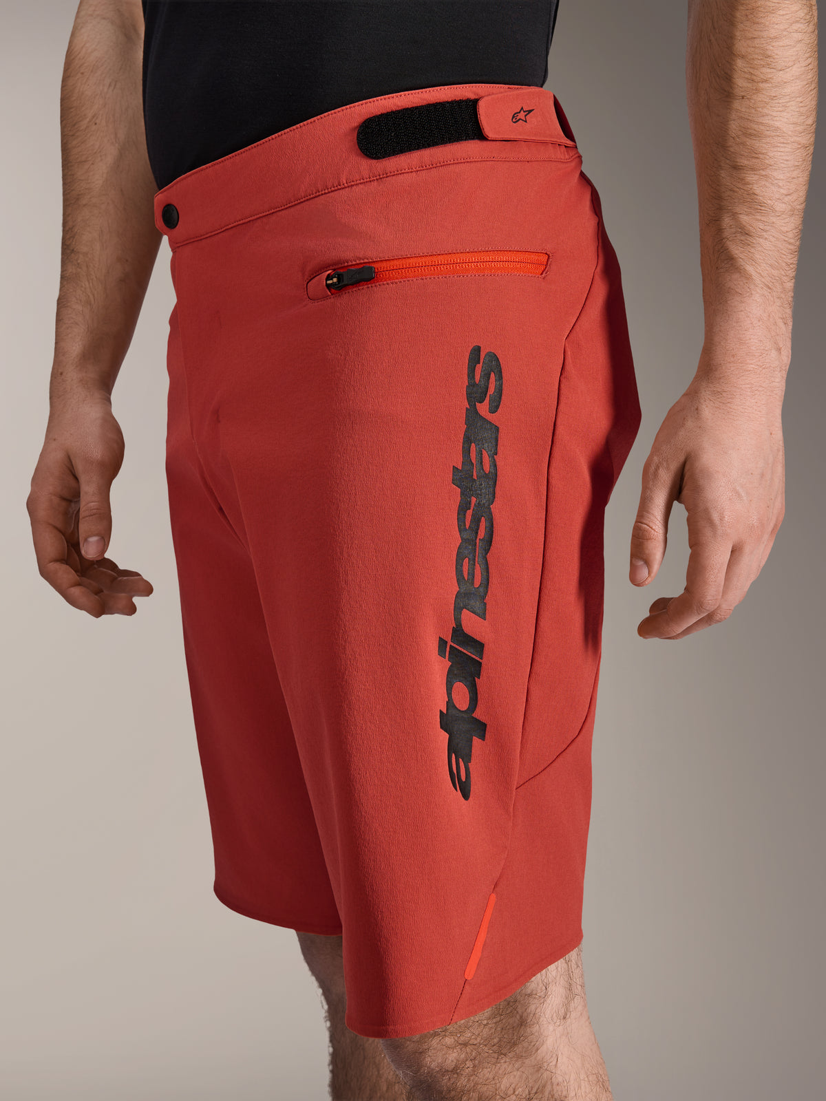 Shorts Alpinestars A-Dura Elite, pantalones cortos para mountain bike, naranja oscuro, con un logotipo vertical negro de Alpinestars en el lateral, bolsillo con cremallera y ajustadores de cintura de gancho y bucle, ropa de ciclismo todoterreno duradera